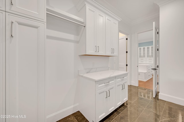 kitchen with light stone counters, crown molding, and white cabinets