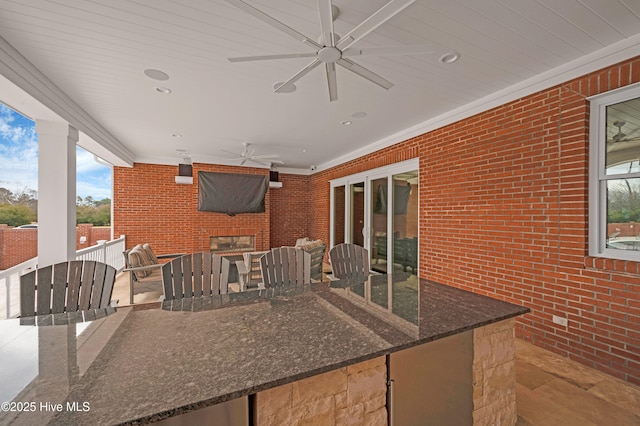 view of patio with an outdoor brick fireplace and ceiling fan