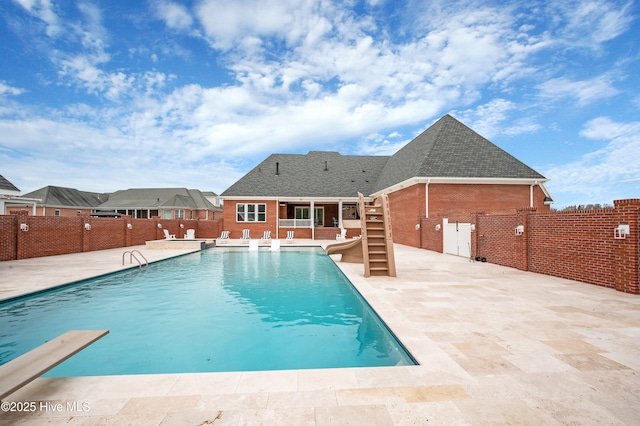 view of swimming pool with a patio area, a diving board, and a water slide