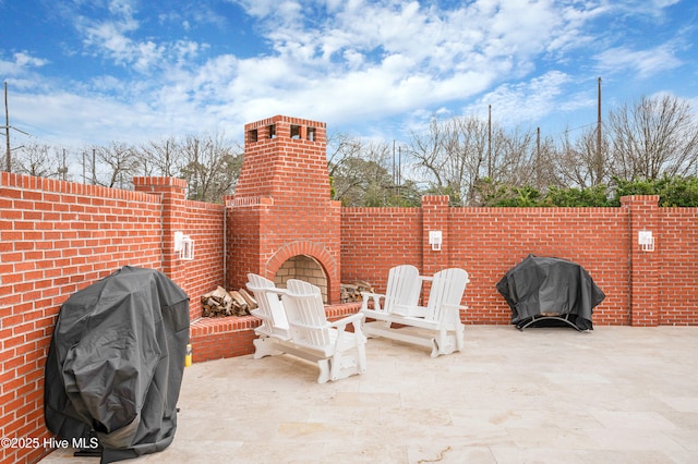 view of patio with an outdoor brick fireplace and grilling area