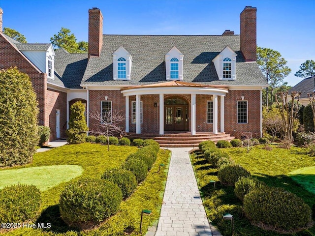 new england style home featuring brick siding, french doors, and a chimney