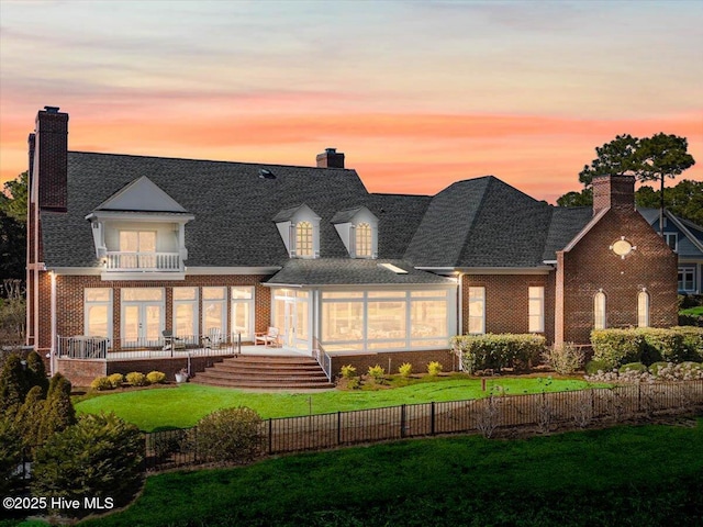 4174 Brookfield Way, Southport, NC 28461 - back of house at dusk with a balcony, brick siding, a chimney, and french doors