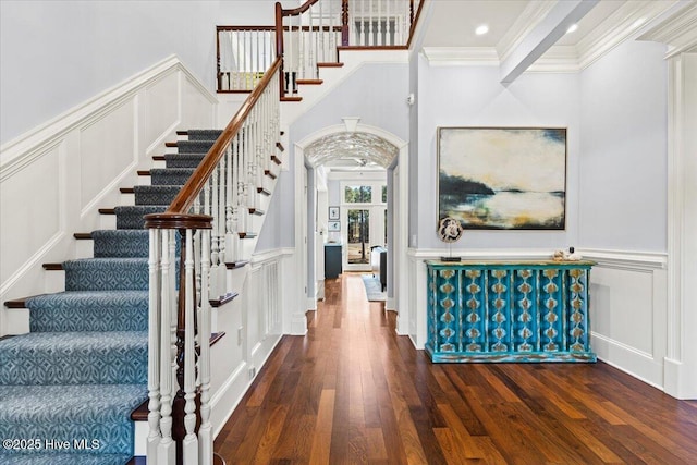 interior space featuring crown molding, a wainscoted wall, a decorative wall, and wood finished floors