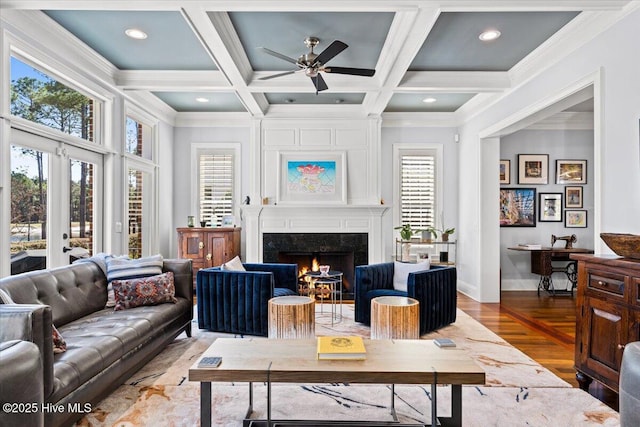 living room with ceiling fan, a high end fireplace, crown molding, baseboards, and beamed ceiling