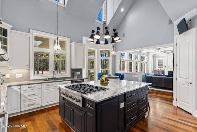 kitchen with a sink, high vaulted ceiling, stainless steel gas cooktop, and white cabinetry