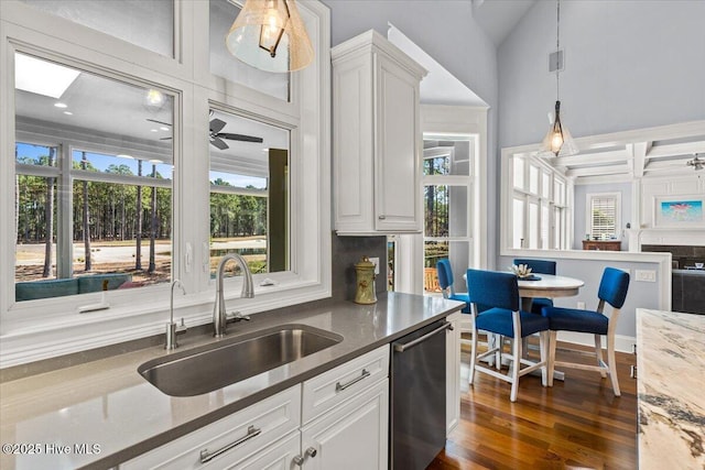 kitchen with stainless steel dishwasher, a sink, a healthy amount of sunlight, and decorative light fixtures