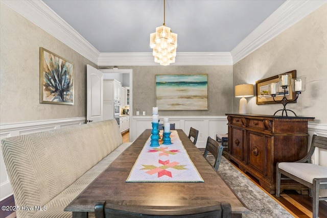 dining room with wainscoting, a decorative wall, and a notable chandelier