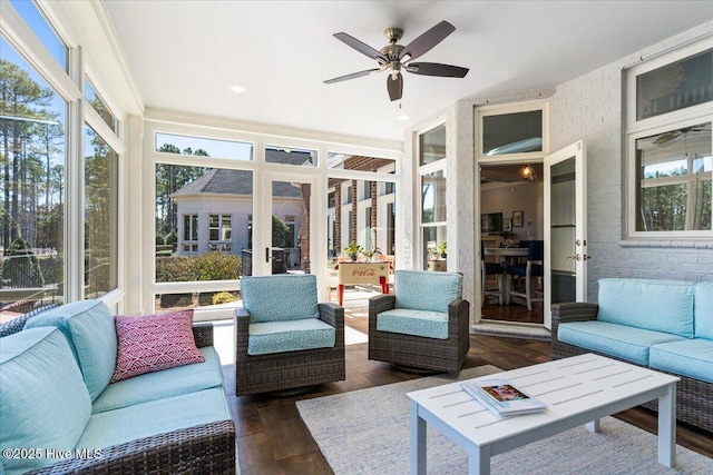 sunroom with ceiling fan, wood finished floors, brick wall, and outdoor lounge area