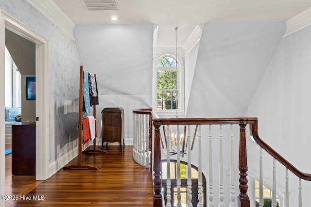 hall with visible vents, ornamental molding, wood finished floors, and an upstairs landing