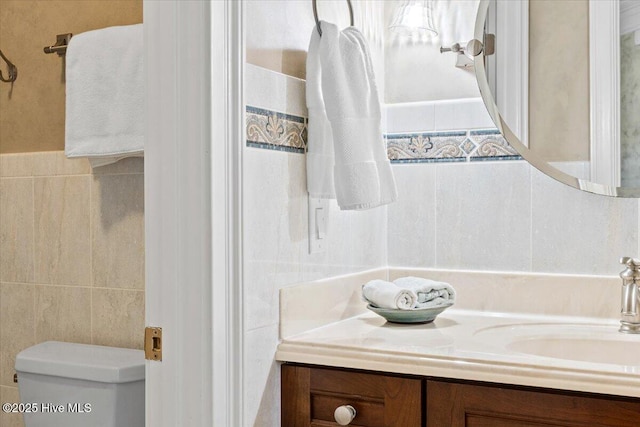bathroom featuring tile walls, vanity, and toilet