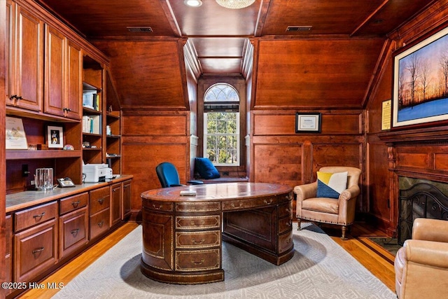 office area with light wood-style floors, wood ceiling, a fireplace, and wood walls