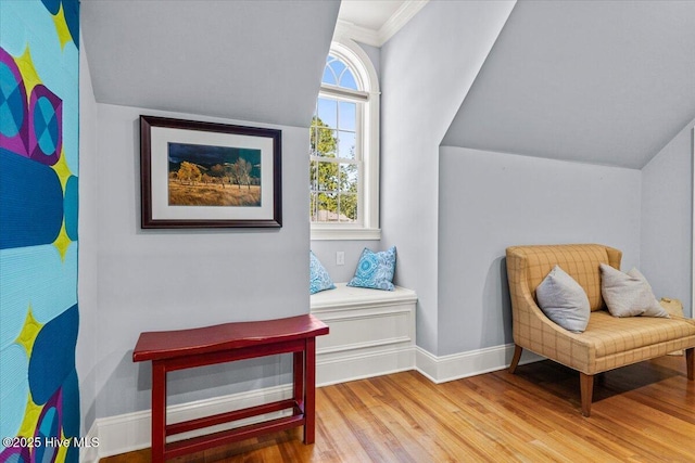 living area with crown molding, baseboards, vaulted ceiling, and wood finished floors