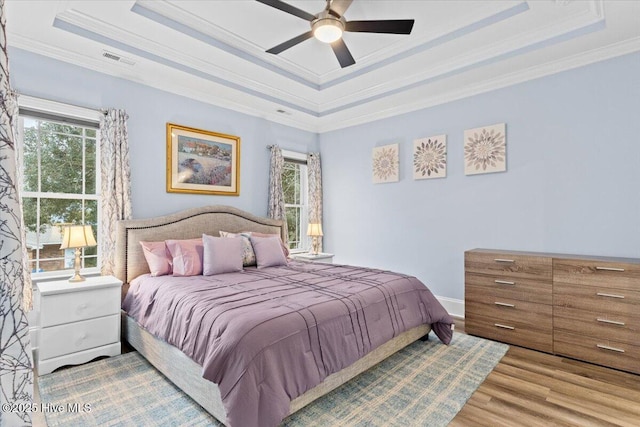 122 NW 19th St, Oak Island, NC 28465 - bedroom featuring a tray ceiling, crown molding, visible vents, and wood finished floors