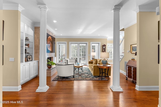 entryway featuring hardwood / wood-style floors, decorative columns, and a large fireplace