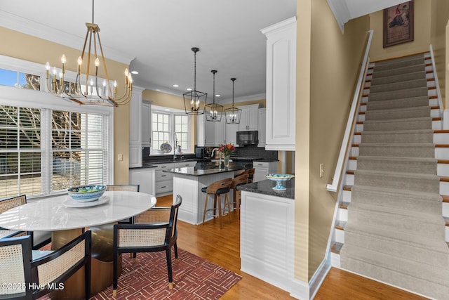 kitchen with a breakfast bar area, tasteful backsplash, a center island, hanging light fixtures, and white cabinets