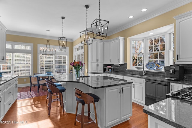 kitchen with sink, dishwasher, white cabinetry, dark stone countertops, and a kitchen island