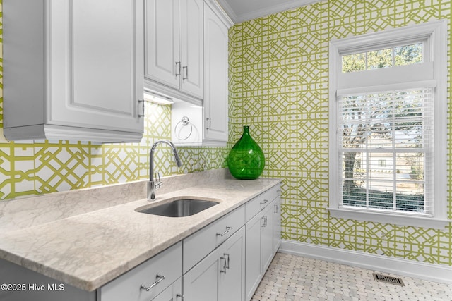 kitchen with sink, white cabinets, decorative backsplash, ornamental molding, and light stone counters