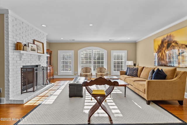 living room with ornamental molding, a brick fireplace, and light wood-type flooring