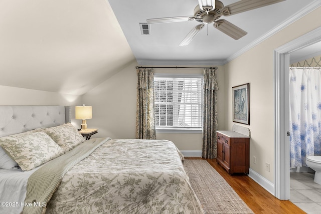 bedroom featuring lofted ceiling, crown molding, ensuite bath, ceiling fan, and light hardwood / wood-style floors