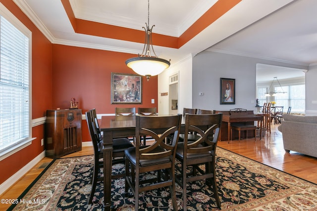 dining area featuring a raised ceiling, ornamental molding, and hardwood / wood-style floors