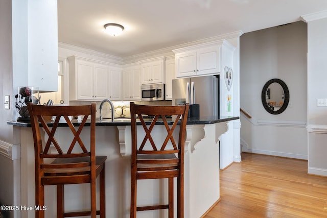 kitchen with a breakfast bar area, stainless steel appliances, kitchen peninsula, and white cabinets