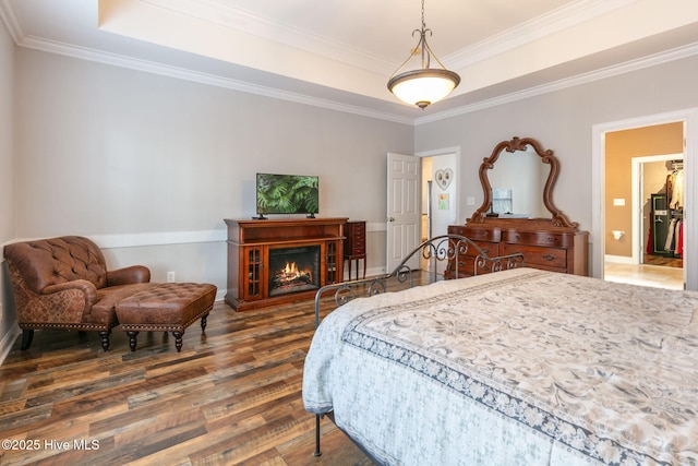 bedroom featuring dark wood-type flooring, crown molding, and a raised ceiling