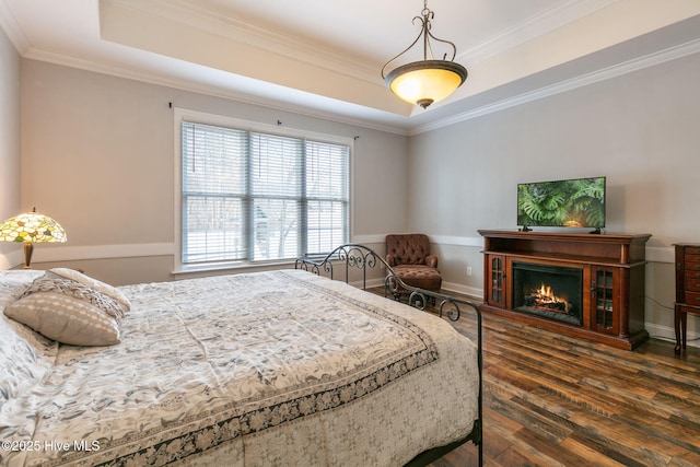 bedroom with dark hardwood / wood-style flooring, a tray ceiling, and crown molding