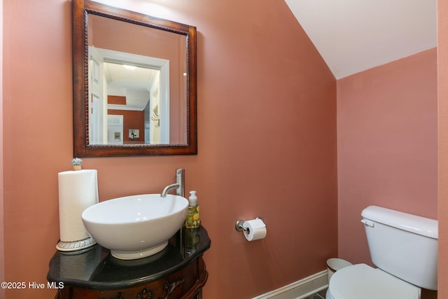 bathroom with vanity, vaulted ceiling, and toilet