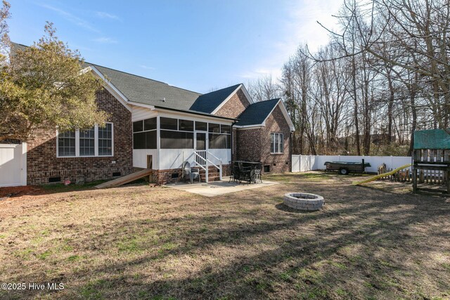 rear view of property with a sunroom, a yard, a patio area, and an outdoor fire pit