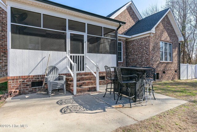 rear view of property featuring a patio, a yard, a fire pit, and a sunroom