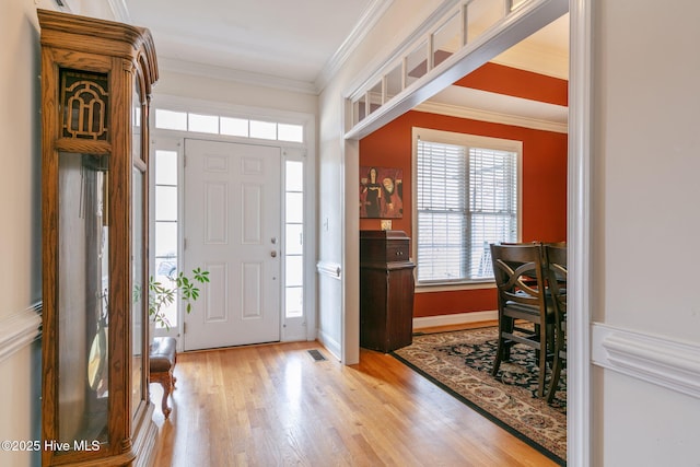 foyer entrance with crown molding and light wood-type flooring