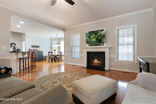 living room with crown molding, ceiling fan with notable chandelier, and light wood-type flooring