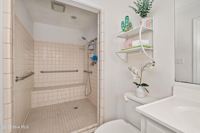 bathroom featuring visible vents, tiled shower, vanity, and toilet