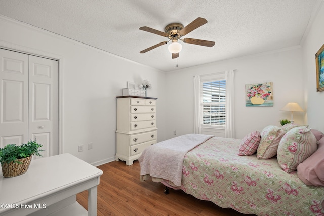 bedroom with ornamental molding, a closet, a textured ceiling, and wood finished floors