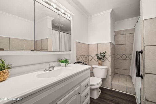 full bath with toilet, wood finished floors, vanity, tile walls, and ornamental molding