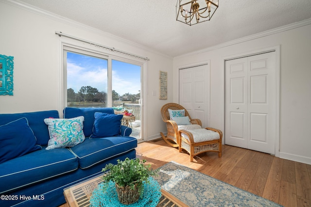 living room with a textured ceiling, ornamental molding, a chandelier, and wood finished floors