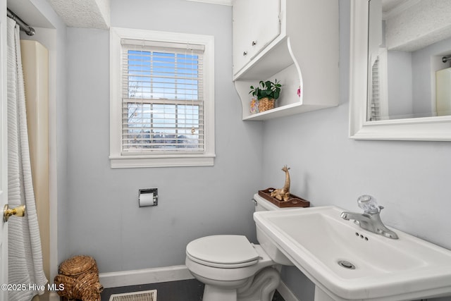 bathroom featuring toilet, visible vents, a sink, and baseboards