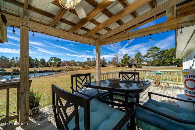 deck with a water view, ceiling fan, a lawn, and outdoor dining space