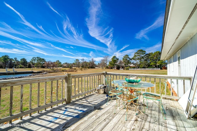 wooden terrace with outdoor dining area and a lawn