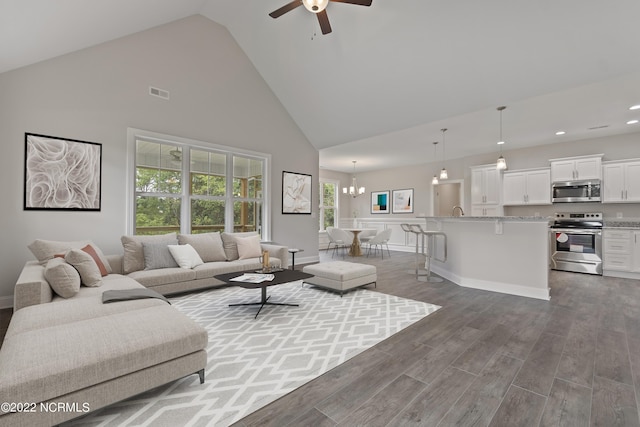 living room with hardwood / wood-style flooring, ceiling fan with notable chandelier, and high vaulted ceiling