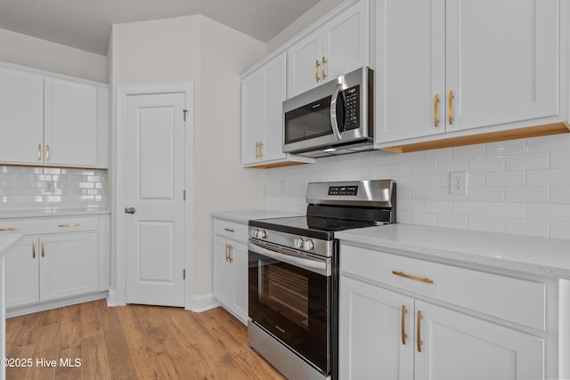 1200 Calabash Station Blvd NW, Calabash, NC 28467 - kitchen featuring stainless steel appliances, white cabinets, light wood-style floors, and tasteful backsplash