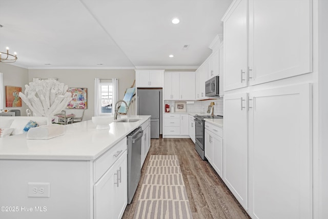 kitchen featuring stainless steel appliances, a kitchen island with sink, sink, and white cabinets