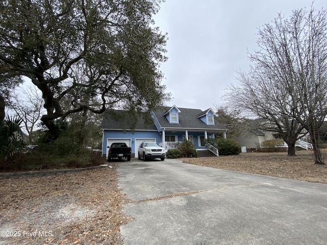 cape cod house featuring a garage and covered porch