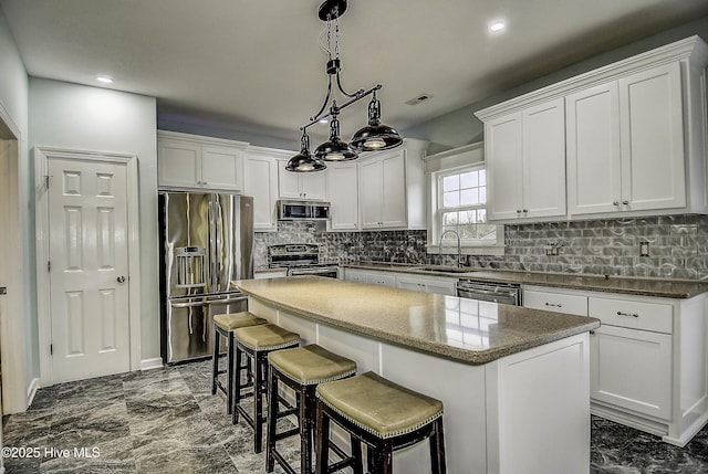 kitchen featuring white cabinetry, hanging light fixtures, stainless steel appliances, and a center island