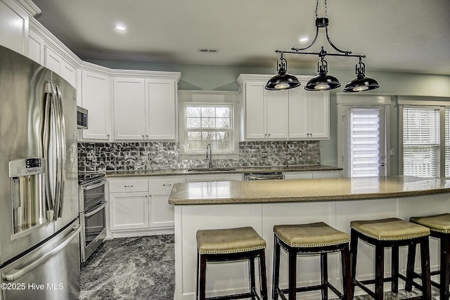 kitchen with sink, white cabinetry, backsplash, stainless steel fridge with ice dispenser, and range with two ovens