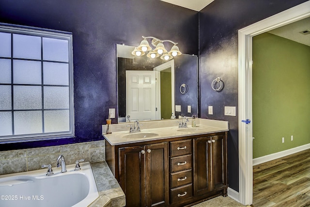 bathroom with vanity, hardwood / wood-style floors, and a relaxing tiled tub