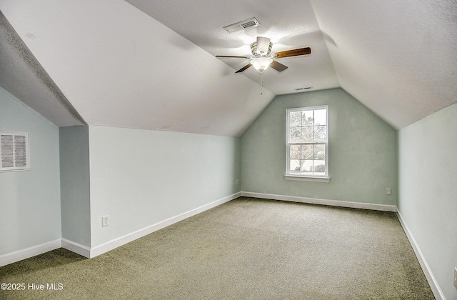 additional living space featuring ceiling fan, lofted ceiling, carpet flooring, and a textured ceiling