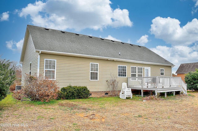 rear view of house featuring a wooden deck and a lawn