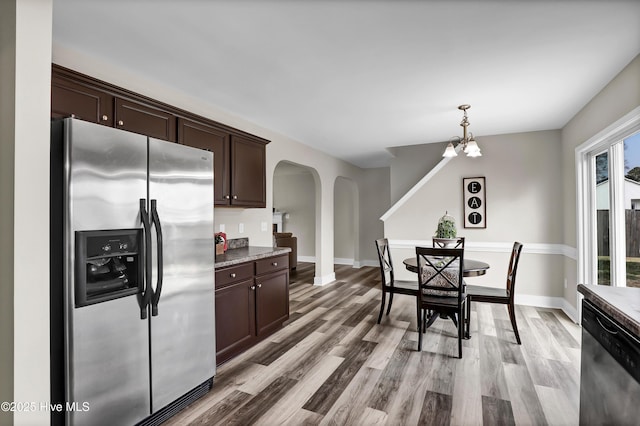 kitchen featuring dark brown cabinetry, appliances with stainless steel finishes, decorative light fixtures, and light hardwood / wood-style floors