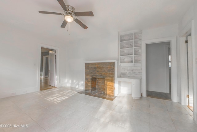 unfurnished living room featuring ceiling fan, a stone fireplace, and light tile patterned floors